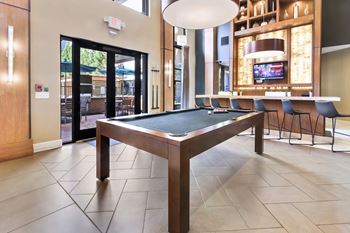 A pool table in a room with a television and a bar.